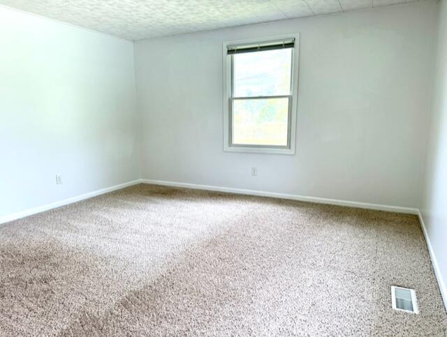 carpeted spare room featuring baseboards and a textured ceiling
