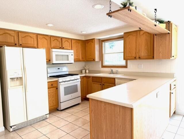 kitchen with white appliances, a peninsula, a sink, light countertops, and light tile patterned floors