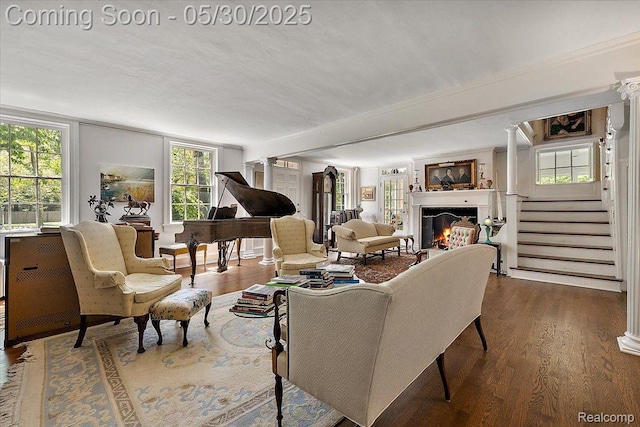 16109 E Jefferson Ave, Grosse Pointe Park, MI 48230 - living area featuring a warm lit fireplace, dark wood-style flooring, stairs, and decorative columns