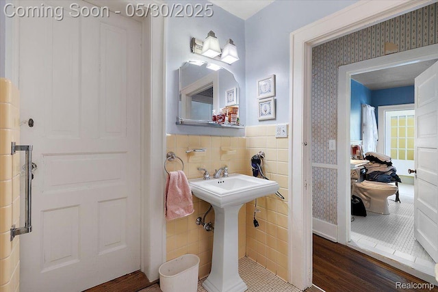 16109 E Jefferson Ave, Grosse Pointe Park, MI 48230 - bathroom featuring tile walls, wallpapered walls, wainscoting, wood finished floors, and a sink