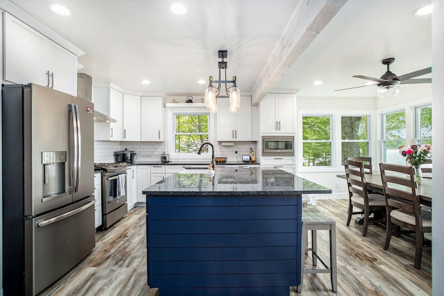 kitchen featuring appliances with stainless steel finishes, light wood-style floors, decorative backsplash, white cabinets, and recessed lighting