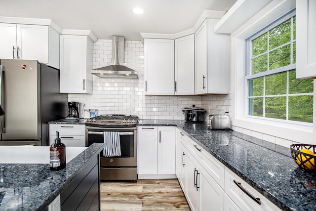 kitchen featuring stainless steel appliances, wall chimney exhaust hood, white cabinetry, recessed lighting, and backsplash