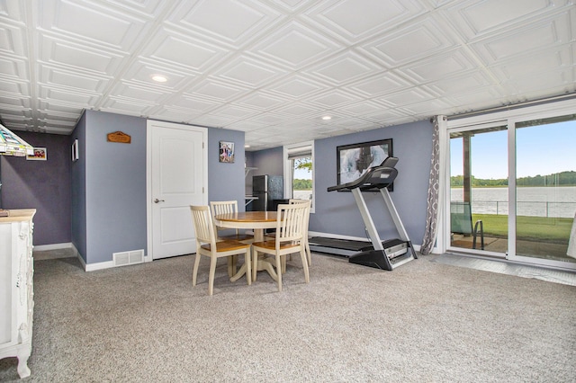 carpeted dining space featuring baseboards, a water view, an ornate ceiling, and recessed lighting