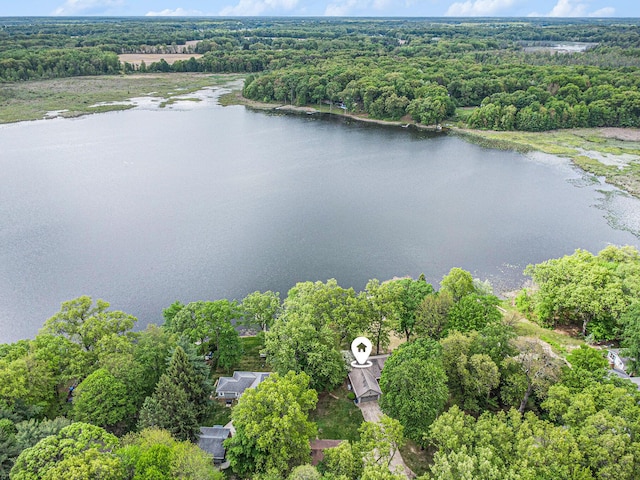 drone / aerial view of a nearby body of water and a heavily wooded area