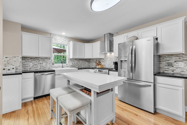 6550 Avon Dr, Brighton, MI 48116 - kitchen featuring stainless steel appliances, wall chimney exhaust hood, a sink, decorative backsplash, and white cabinets