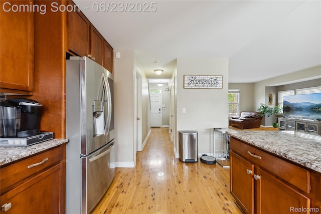 750 2nd St Unit 27, Wyandotte, MI 48192 - kitchen featuring stainless steel fridge, light wood-style floors, open floor plan, and light stone countertops
