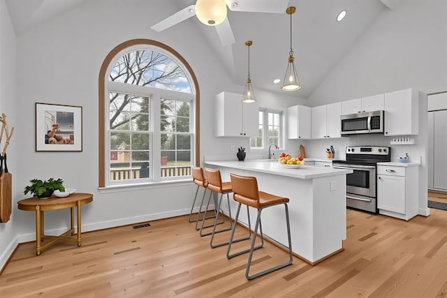 37695 Burton Dr, Farmington Hills, MI 48331 - kitchen featuring appliances with stainless steel finishes, light countertops, light wood-type flooring, white cabinetry, and high vaulted ceiling