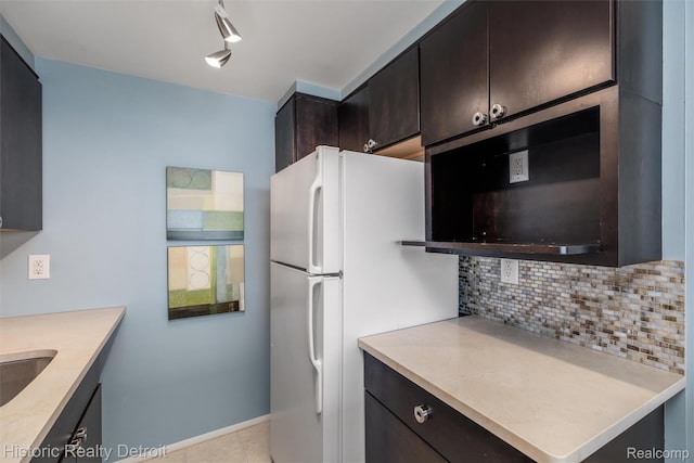 1300 E Lafayette St Unit 2502, Detroit, MI 48207 - kitchen with freestanding refrigerator, tasteful backsplash, light countertops, dark brown cabinets, and baseboards