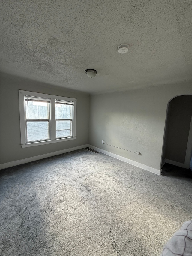 7130 Julian St, Detroit, MI 48204 - empty room featuring carpet floors, a textured ceiling, arched walkways, and baseboards