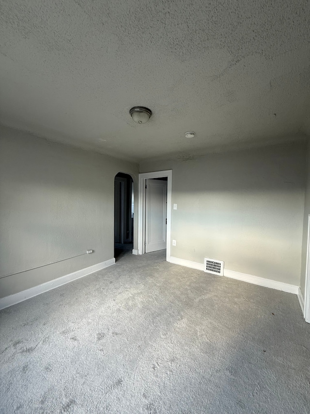 7130 Julian St, Detroit, MI 48204 - empty room featuring arched walkways, carpet flooring, baseboards, and a textured ceiling