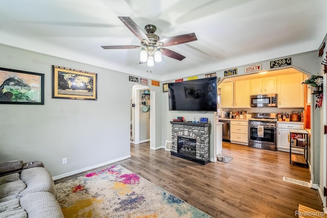706 White Ave, Lincoln Park, MI 48146 - living room featuring ceiling fan, wood finished floors, baseboards, a fireplace, and arched walkways