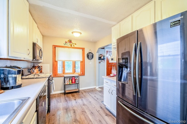 706 White Ave, Lincoln Park, MI 48146 - kitchen featuring stainless steel appliances, a textured ceiling, light countertops, a sink, and light wood-style flooring