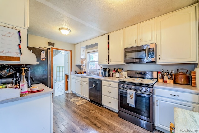 706 White Ave, Lincoln Park, MI 48146 - kitchen with appliances with stainless steel finishes, a textured ceiling, light wood-style flooring, white cabinets, and light countertops