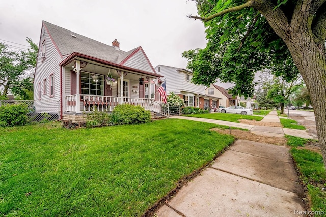 706 White Ave, Lincoln Park, MI 48146 - view of front of home featuring covered porch, a chimney, a front lawn, and roof with shingles