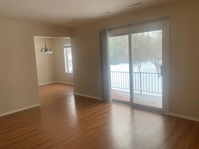 311 W Highland Rd Unit T13, Howell, MI 48843 - unfurnished room featuring a chandelier, wood finished floors, and baseboards