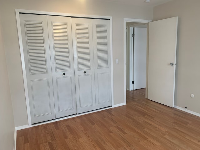 311 W Highland Rd Unit T13, Howell, MI 48843 - unfurnished bedroom featuring a closet, wood finished floors, and baseboards