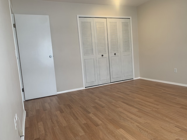 311 W Highland Rd Unit T13, Howell, MI 48843 - unfurnished bedroom featuring wood finished floors, a closet, and baseboards