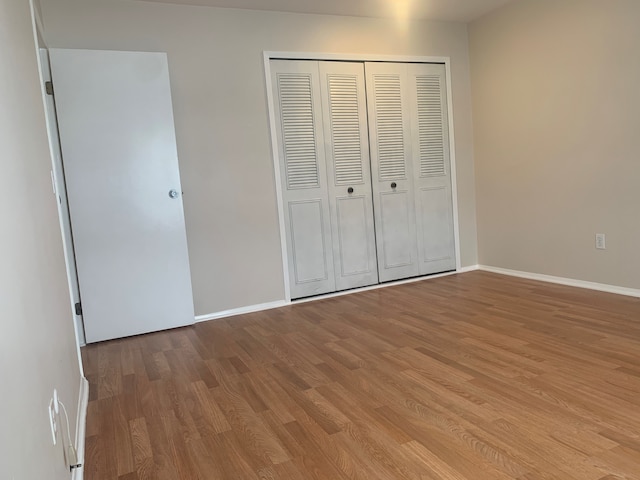 311 W Highland Rd Unit T13, Howell, MI 48843 - unfurnished bedroom featuring wood finished floors, a closet, and baseboards