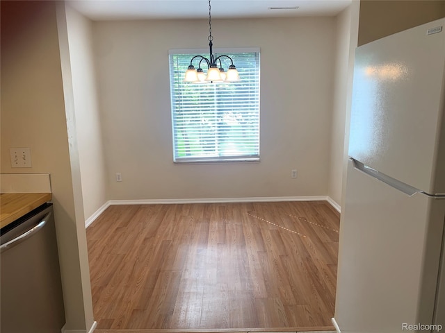 311 W Highland Rd Unit T13, Howell, MI 48843 - unfurnished dining area with light wood-type flooring, baseboards, and a chandelier