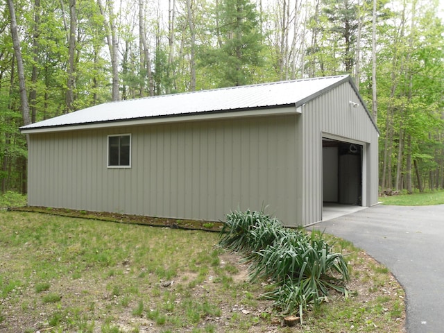 6515 Maple Rd, Ludington, MI 49431 - view of side of home with a garage, an outbuilding, metal roof, asphalt driveway, and a wooded view