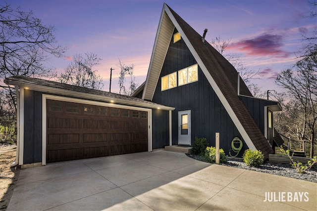 a-frame style home featuring board and batten siding, an attached garage, and driveway
