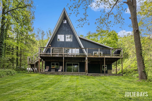 rear view of property with a deck, a lawn, and stairs