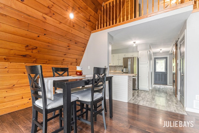 dining room featuring dark wood finished floors and wooden walls
