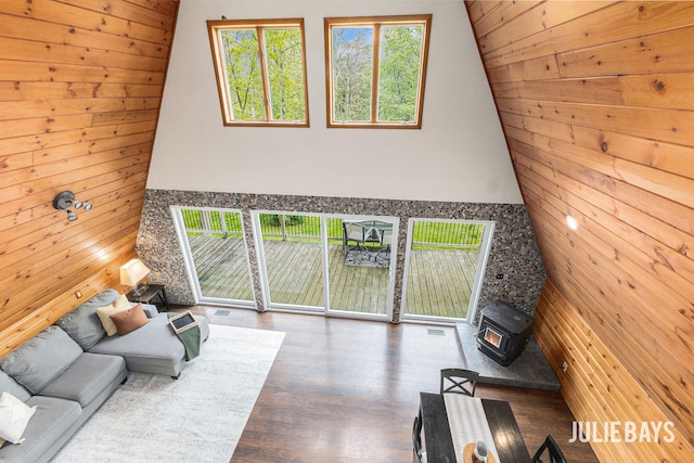 living room with wooden walls, wood finished floors, lofted ceiling, and a wood stove