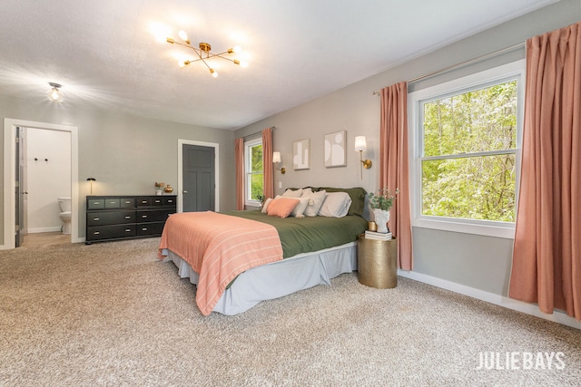 bedroom featuring carpet floors, baseboards, ensuite bathroom, and a chandelier