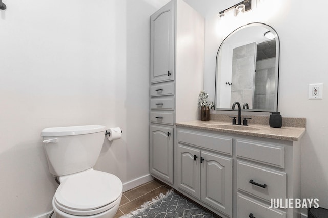 bathroom with baseboards, toilet, vanity, and wood finished floors