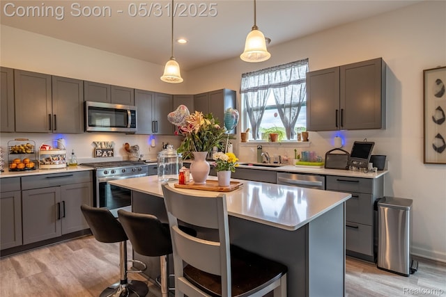9480 White Tail Dr, Ypsilanti, MI 48197 - kitchen with stainless steel appliances, a breakfast bar, light wood-type flooring, light countertops, and a center island