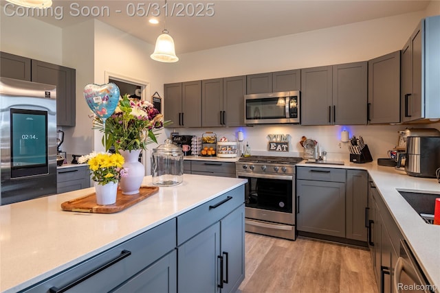 9480 White Tail Dr, Ypsilanti, MI 48197 - kitchen with stainless steel appliances, light countertops, light wood finished floors, decorative light fixtures, and gray cabinetry