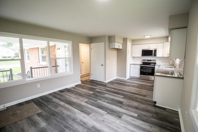kitchen featuring appliances with stainless steel finishes, a sink, healthy amount of natural light, and baseboards