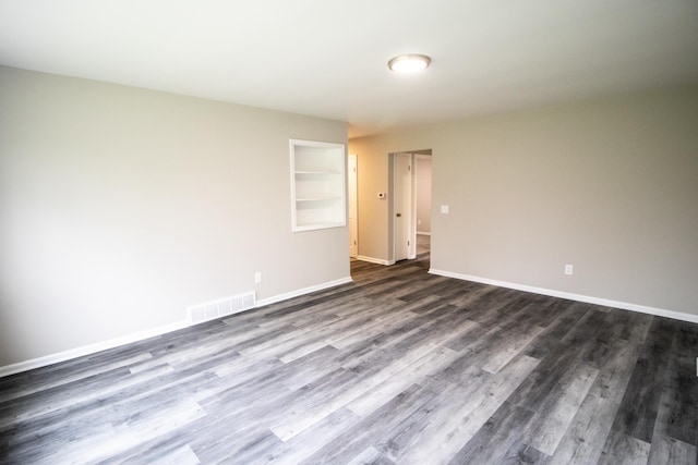 unfurnished room with dark wood-style floors, built in features, and baseboards