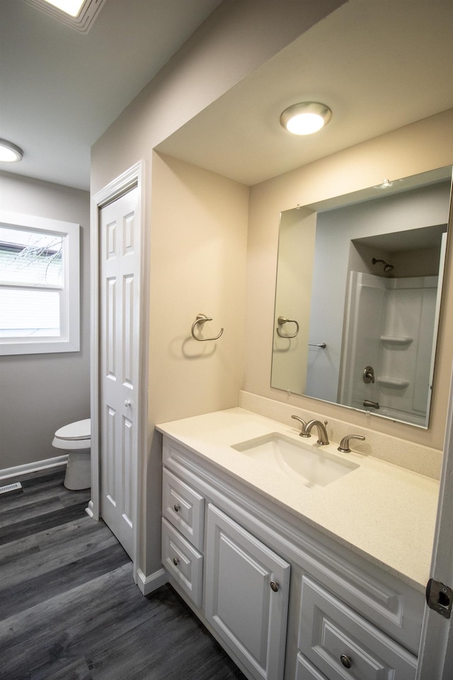 full bath with toilet, wood finished floors, vanity, a shower, and baseboards
