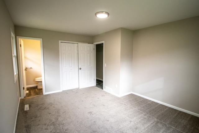 unfurnished bedroom featuring carpet, baseboards, a closet, and ensuite bath