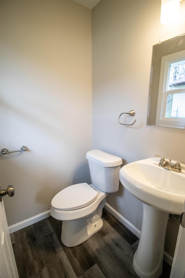 bathroom featuring wood finished floors, toilet, baseboards, and a sink