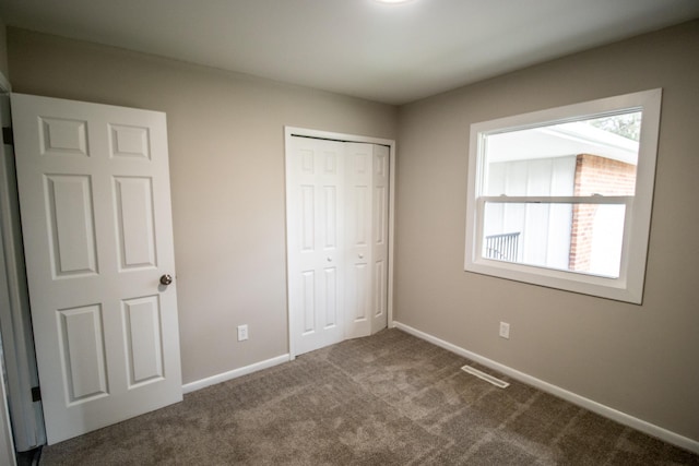 unfurnished bedroom with multiple windows, carpet floors, a closet, and baseboards