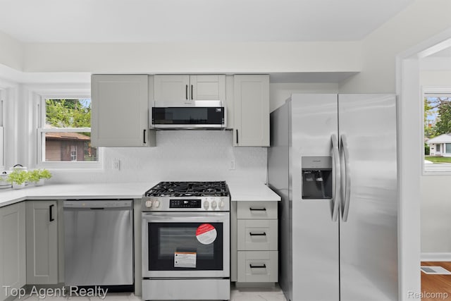 32525 Holden Dr, Warren, MI 48092 - kitchen with appliances with stainless steel finishes, gray cabinetry, light countertops, and decorative backsplash