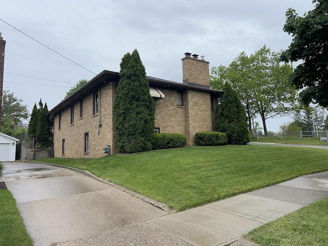 805 Capen St NE, Grand Rapids, MI 49505 - view of side of property with brick siding, a chimney, a yard, and concrete driveway