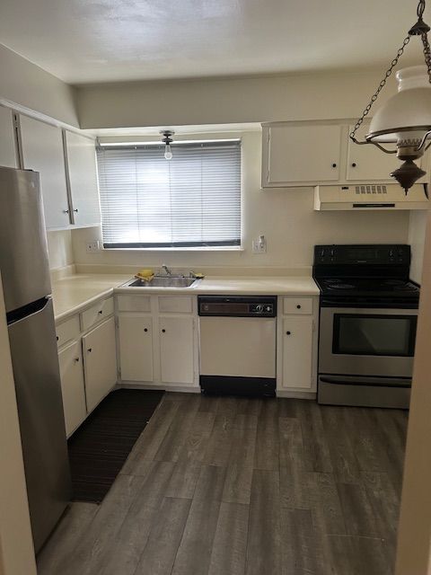 25332 Shiawassee Cir, Southfield, MI 48033 - kitchen featuring stainless steel appliances, under cabinet range hood, a sink, white cabinets, and dark wood finished floors