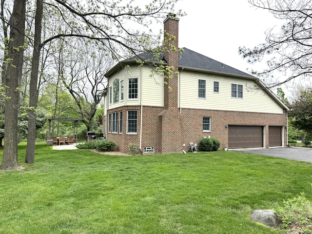 2129 Autumn Hill Dr, Ann Arbor, MI 48103 - view of side of property with brick siding, a chimney, an attached garage, asphalt driveway, and a lawn