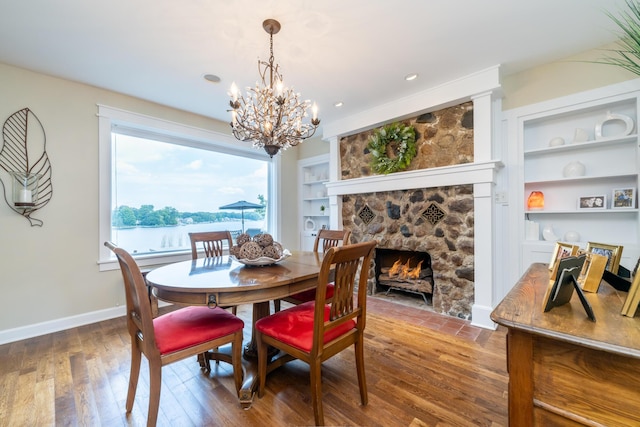 7881 Lakewood Dr, Coloma, MI 49038 - dining space featuring wood finished floors, built in features, a chandelier, a fireplace, and baseboards