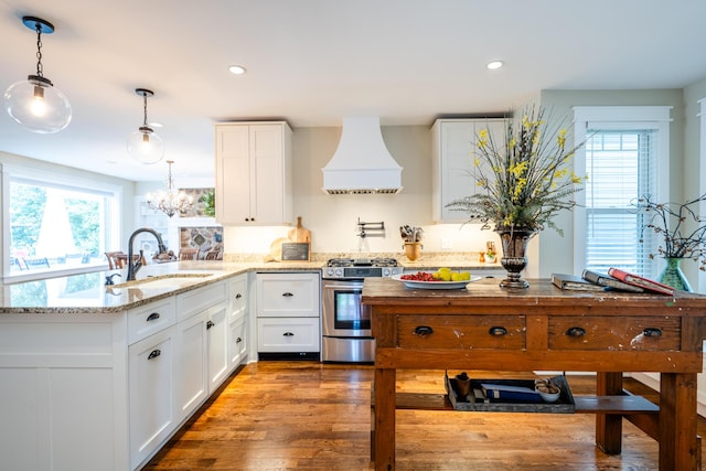 7881 Lakewood Dr, Coloma, MI 49038 - kitchen with stainless steel range with gas cooktop, premium range hood, a sink, a peninsula, and white cabinetry