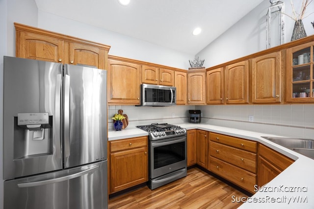 1323 Gleneagle Pl Unit 7, Hudsonville, MI 49426 - kitchen featuring stainless steel appliances, tasteful backsplash, lofted ceiling, light wood-type flooring, and light countertops