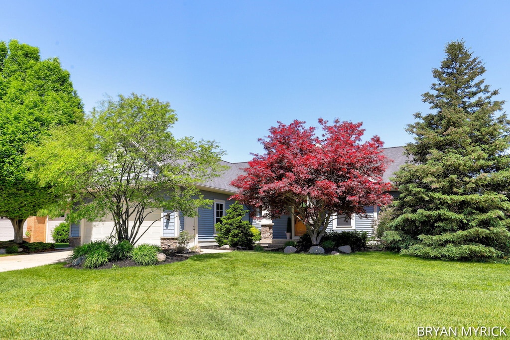 2655 Hawthorne Ct, Jenison, MI 49428 - view of property hidden behind natural elements featuring a front yard, a garage, and concrete driveway