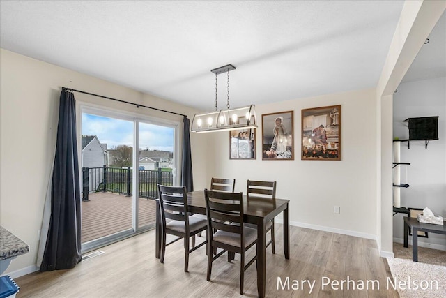 dining room with light wood-style floors, baseboards, and a chandelier