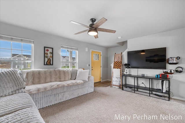 carpeted living area with a ceiling fan and baseboards