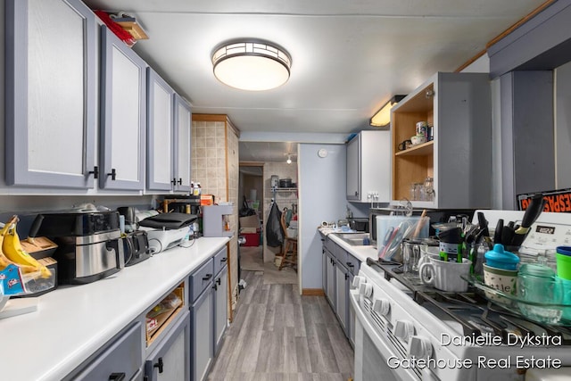 11660 Wren Dr, Lakeview, MI 48850 - kitchen with white range with gas cooktop, light wood-style flooring, light countertops, and gray cabinetry