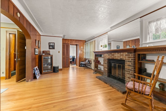 449 Spruce St, Wyandotte, MI 48192 - living room featuring light wood-type flooring, crown molding, an ornate ceiling, arched walkways, and a brick fireplace